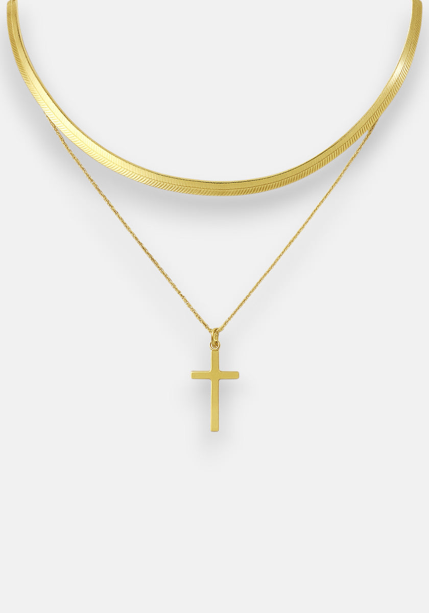 Two gold necklaces by Princess Goes Hollywood: a flat, wide Schlangenkette with a shiny finish, and a thin Halskette Goldoptik with a simple Kreuzanhänger. Both are shown against a plain, light background.