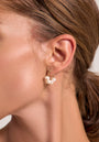 Close-up of a woman’s ear adorned with Princess Goes Hollywood Creolen, crafted from 925 sterling silver and embellished with small freshwater pearls. Her pulled-back brown hair enhances the earring’s elegance against her smooth, light skin.