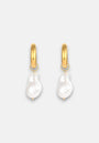 Princess Goes Hollywood 18K gold-plated stainless steel hoops each showcase a single, irregular freshwater pearl drop hanging on small gold loops, offering a modern, elegant look against a light gray background.