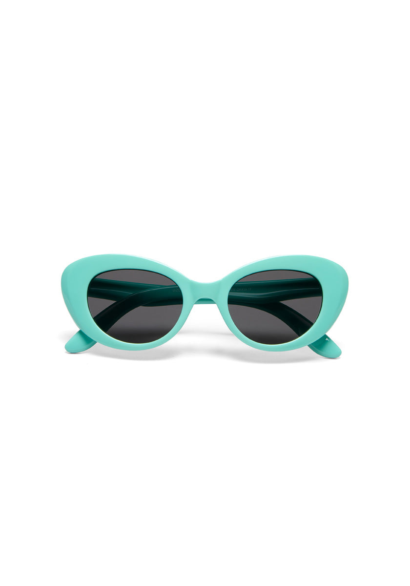 A pair of Okkia cat-eye sunglasses from the Kollektion with thick, glossy, light turquoise blue frames and dark tinted lenses, shown facing forward against a plain white background.