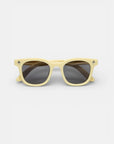 Okkia Sonnenbrille aus der Kollektion, mit einem hellgelben rechteckigen TPEE-Rahmen und dunkel getönten Gläsern. Kleine schwarze Kreuze akzentuieren jede obere Ecke, abgebildet auf einem schlichten weißen Hintergrund.