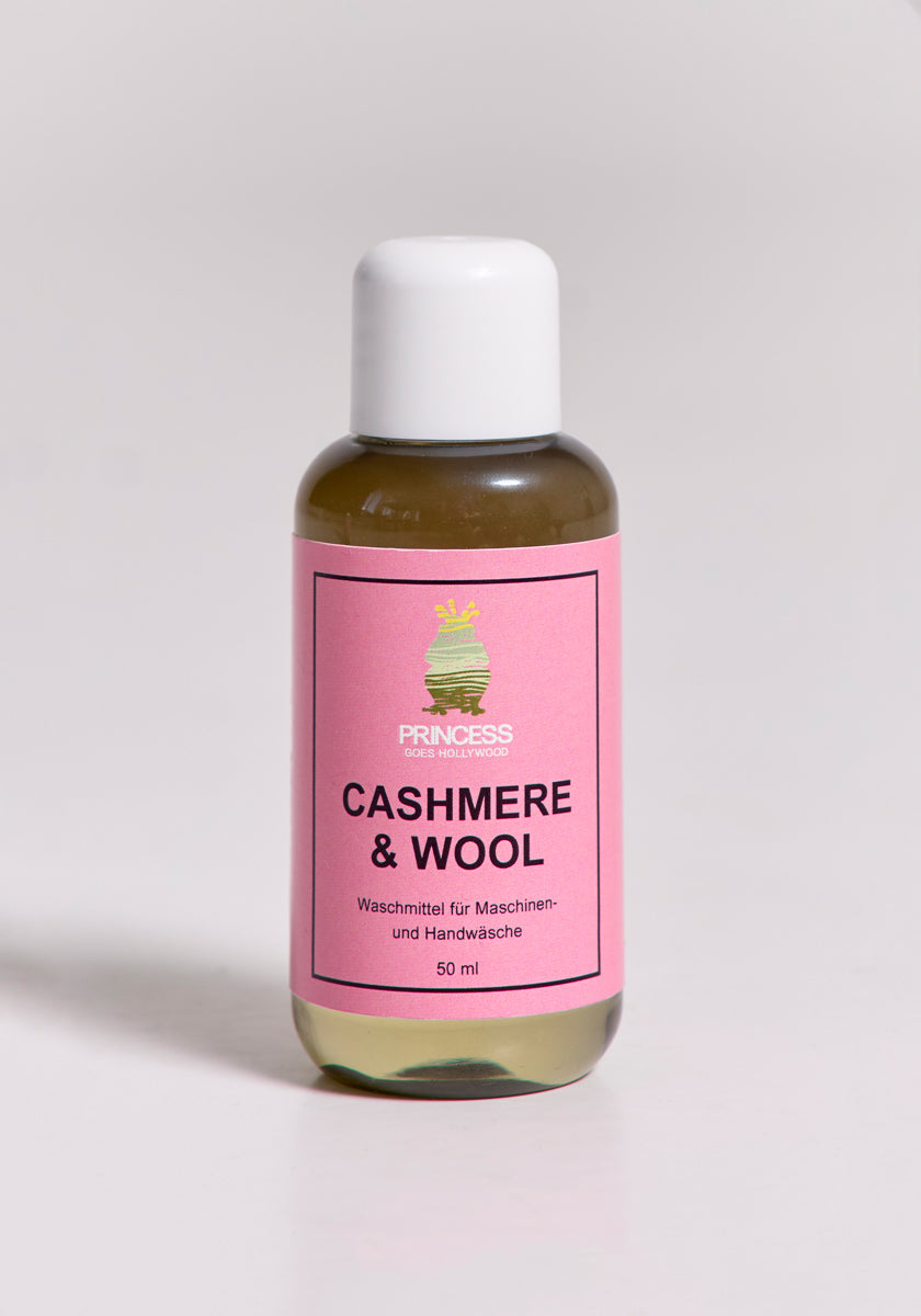 Eine klare 50-ml-Plastikflasche mit weißem Verschluss steht auf einer hellen Fläche. Das rosafarbene Etikett trägt die Aufschrift "Princess Goes Hollywood" und ist mit Cashmere Waschmittel und Wollpflege für Maschinen- oder Handwäsche versehen.