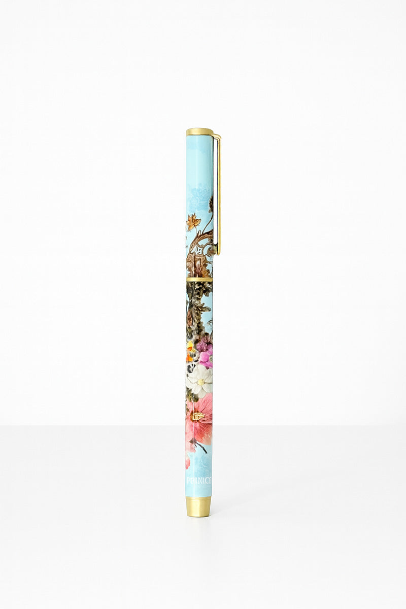 A Princess Goes Hollywood Kugelschreiber stands upright against a white background, featuring gold accents and a blue floral design with birds and “PENNIC” at the bottom—an elegant match for your 2026 Terminplaner or Notiz.