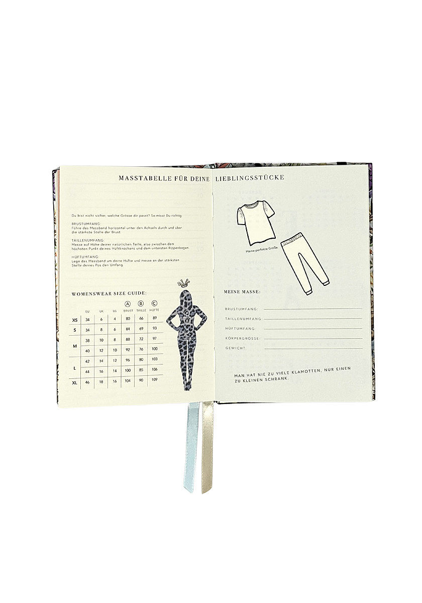 An open Princess Goes Hollywood notebook, likely a Jahresplaner 2026, features a women’s clothing size chart, a female silhouette, shirt and pants sketches, German headings on the pages, and fabric bookmarks hanging from the spine.