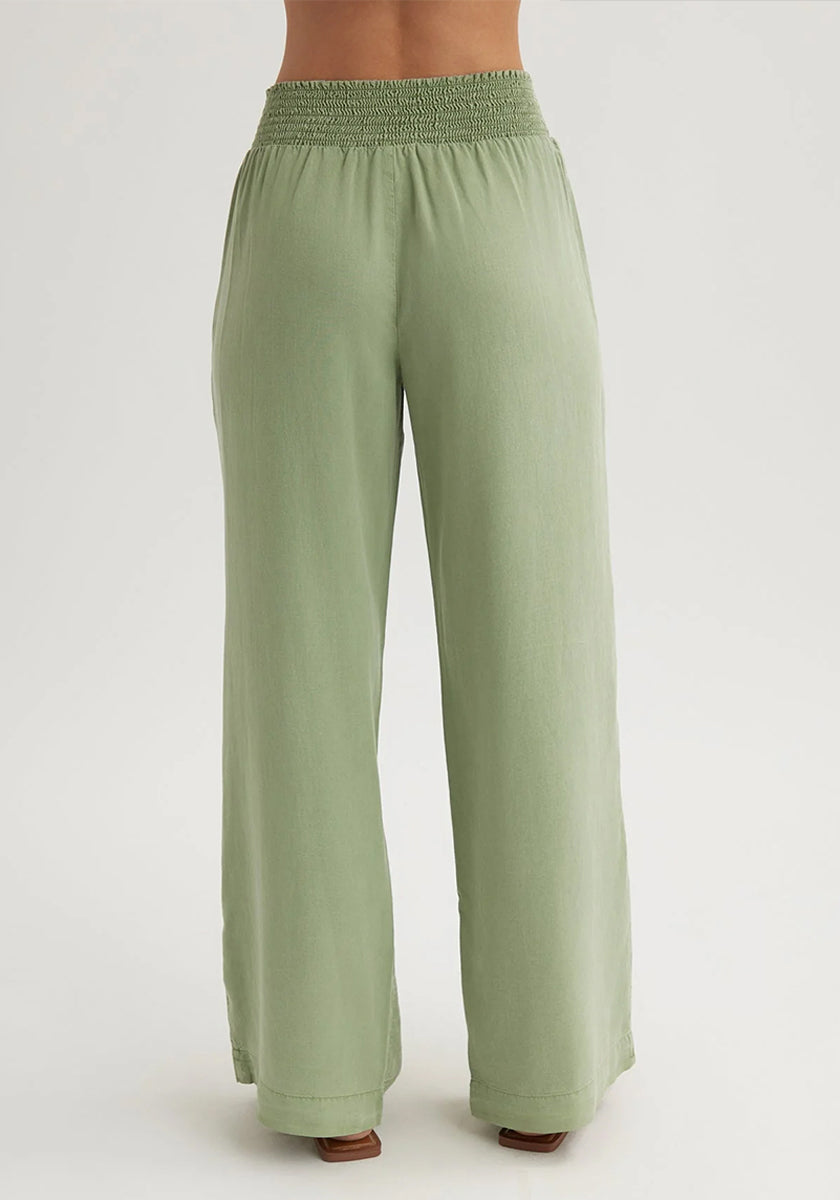 A person is shown from waist to ankles, wearing Bella Dahls wide-leg Lyocell trousers in light sage green with an elastic shirred waistband, standing against a plain light background.