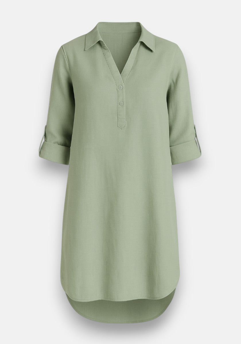 The Bella Dahl sage green Lyocell Kleid is a relaxed A-line, knee-length shirt dress with a V-neck, partial button placket, collar, rolled long sleeves with buttoned tabs, and a curved hem for minimalist style.