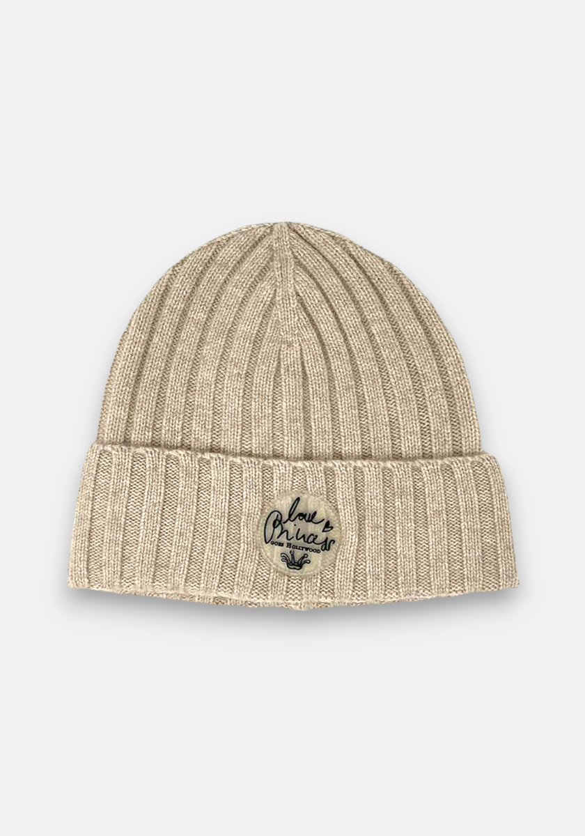 A beige ribbed knit beanie by Princess Goes Hollywood features a folded brim, Love Africa in black embroidery above a small African continent outline. The background is plain white.