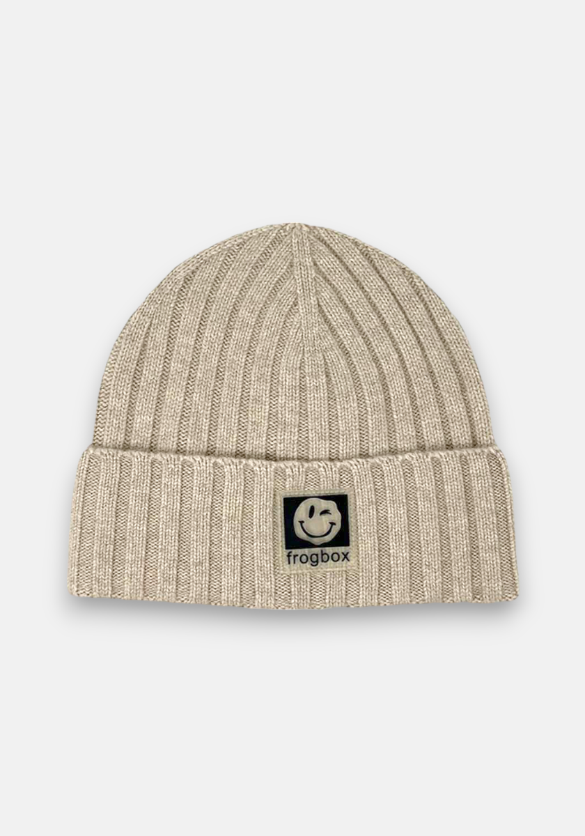 A beige Princess Goes Hollywood Kaschmir beanie with a ribbed design, folded brim, and a black and white front patch showing a smiling frog face above the text frogbox, photographed on a plain white background.