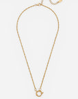 Eine Goldkette von Princess Goes Hollywood mit einer zarten, gedrehten Gliederkette und einem übergroßen, runden Anhänger in Form eines Verschlusses. Die Kette ist aus strapazierfähigem Titanstahl mit luxuriöser 18-Karat-Vergoldung gefertigt und verfügt über eine verstellbare Verlängerungskette sowie ein kleines ovales Etikett am Ende – alles vor einem weißen Hintergrund.