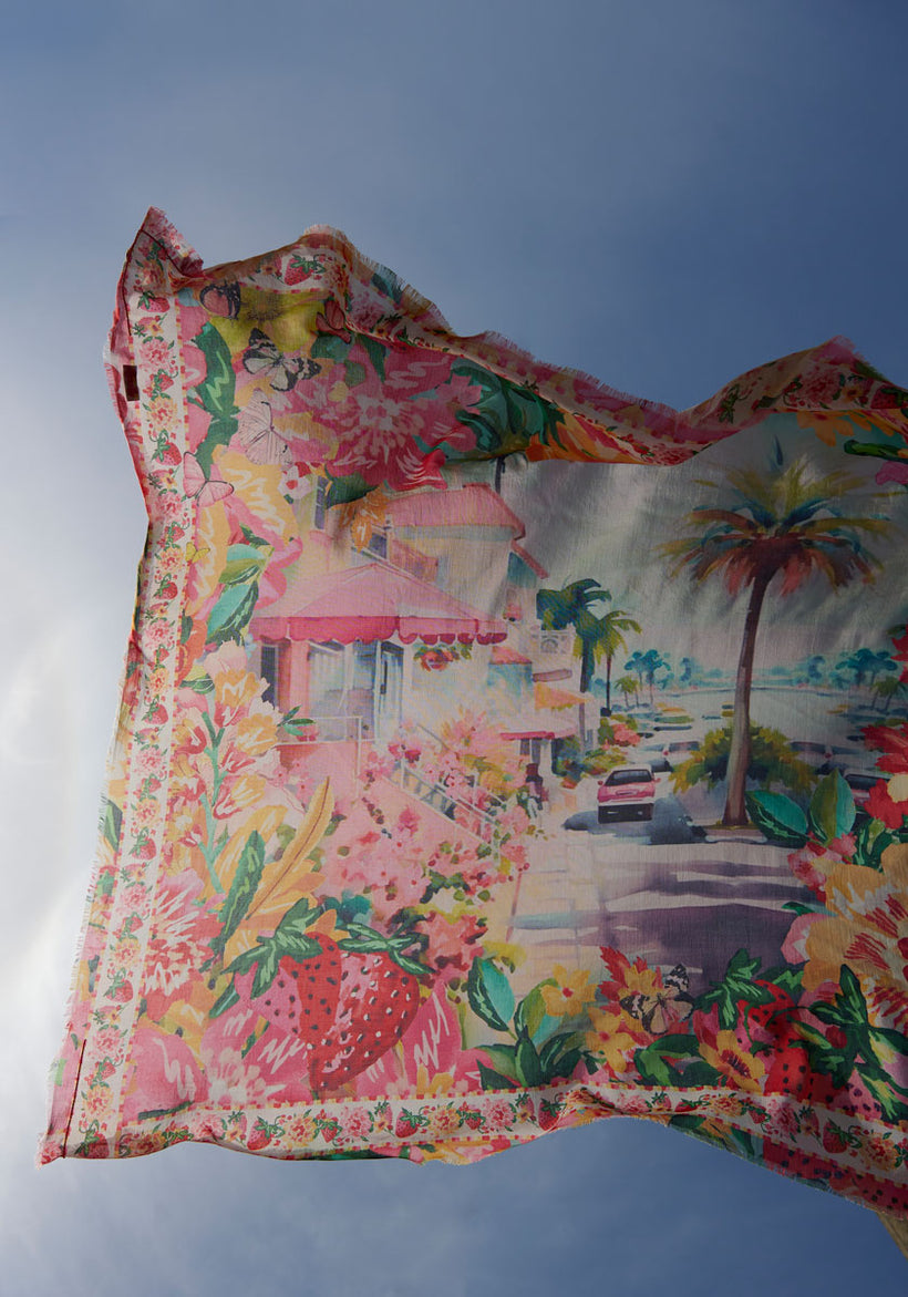 A vibrant Princess Goes Hollywood quadratisches Tuch features colorful floral edges and a lively scene of palm trees, vintage cars, and pink buildings, set against a blue sky for a dreamy, summery vibe.