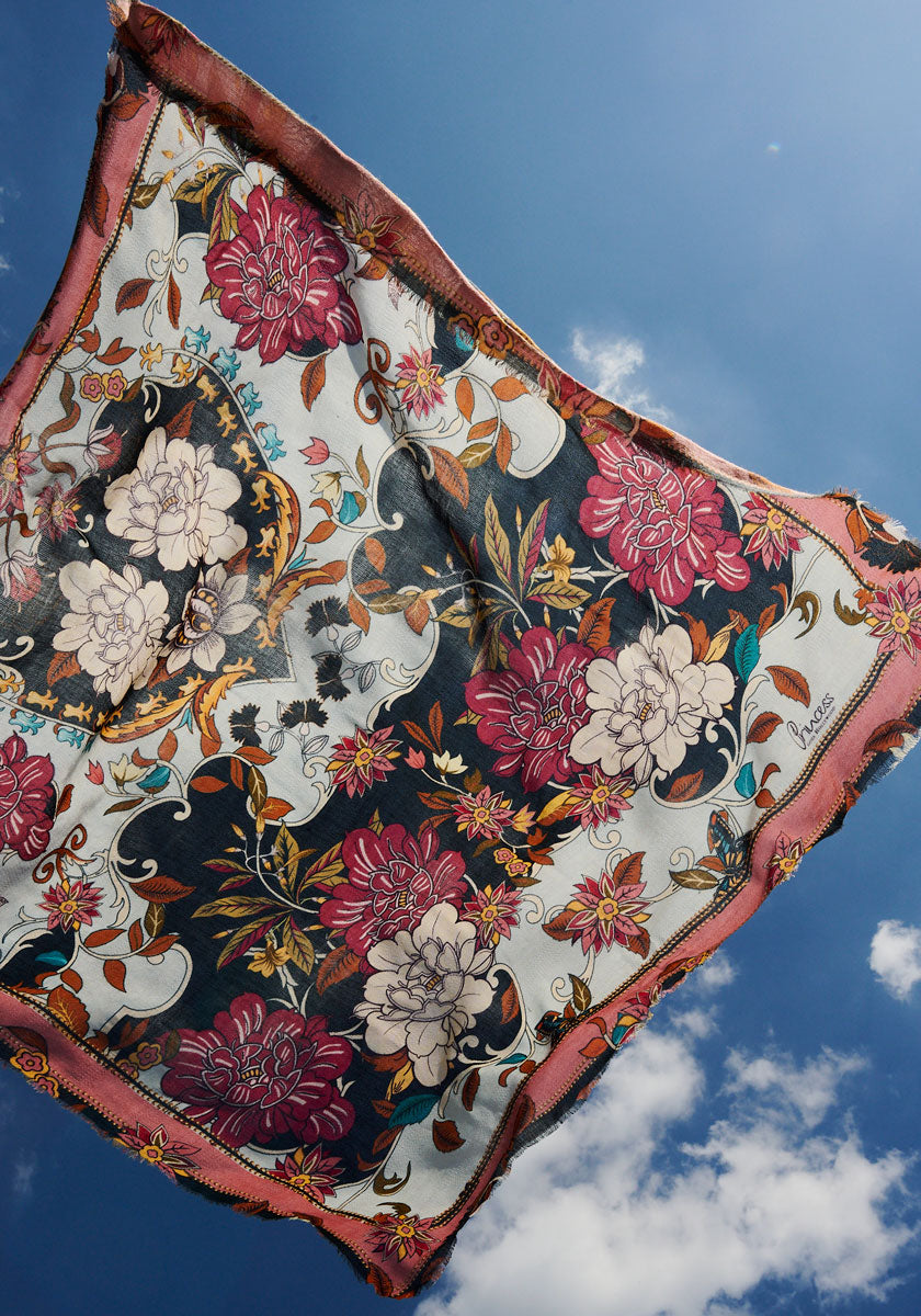 A rectangular scarf by Princess Goes Hollywood made from a cotton-wool blend showcases retro floral and leaf designs in red, pink, and cream, accented with a frayed reddish-brown border.