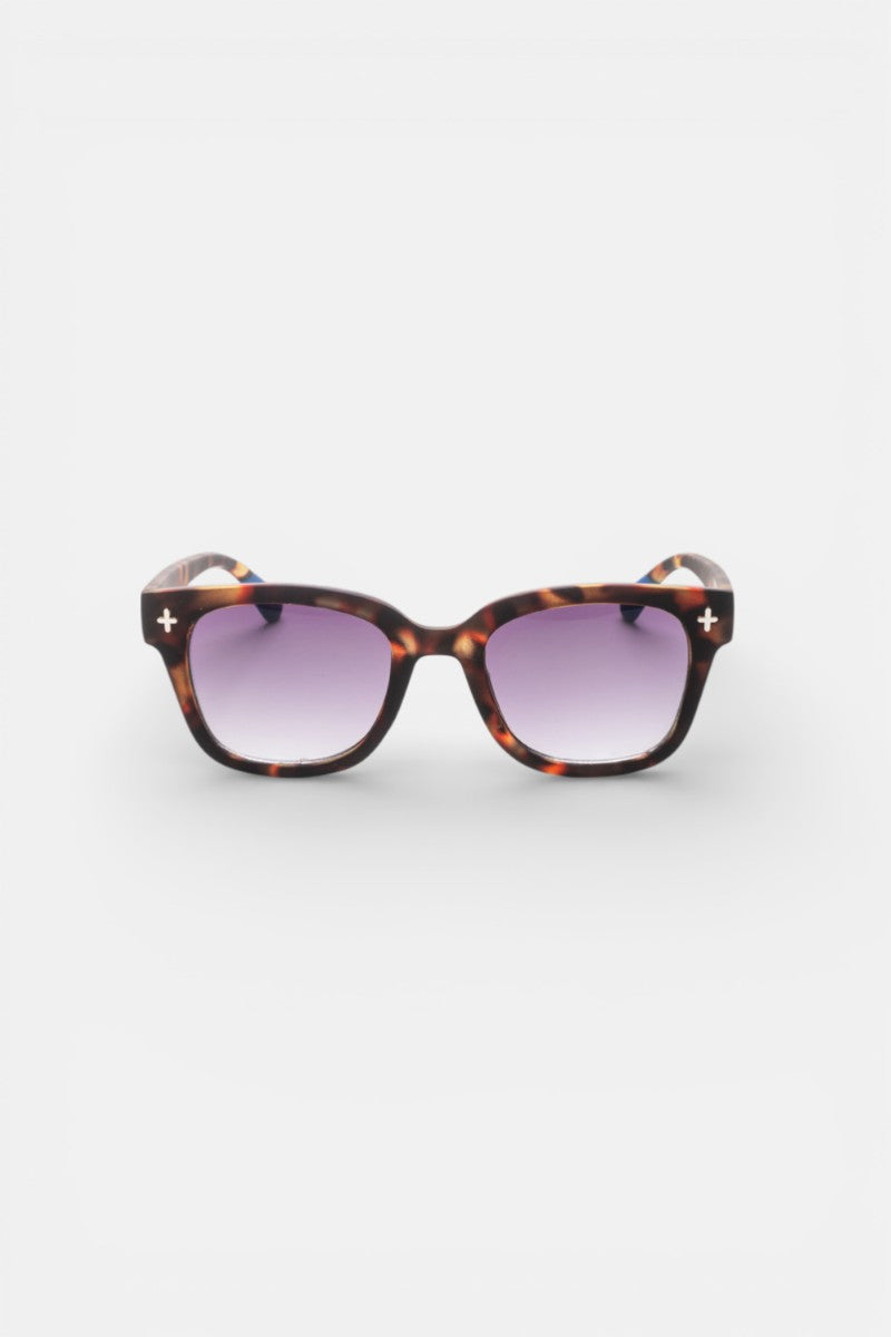 Eine Sonnenbrille aus Schildpatt von Okkia mit quadratischem Rahmen und lila Verlaufsgläsern. Die Rahmen haben kleine weiße Kreuz Akzente an den oberen Ecken. Die Sonnenbrille ist auf einem schlichten weißen Hintergrund zentriert.