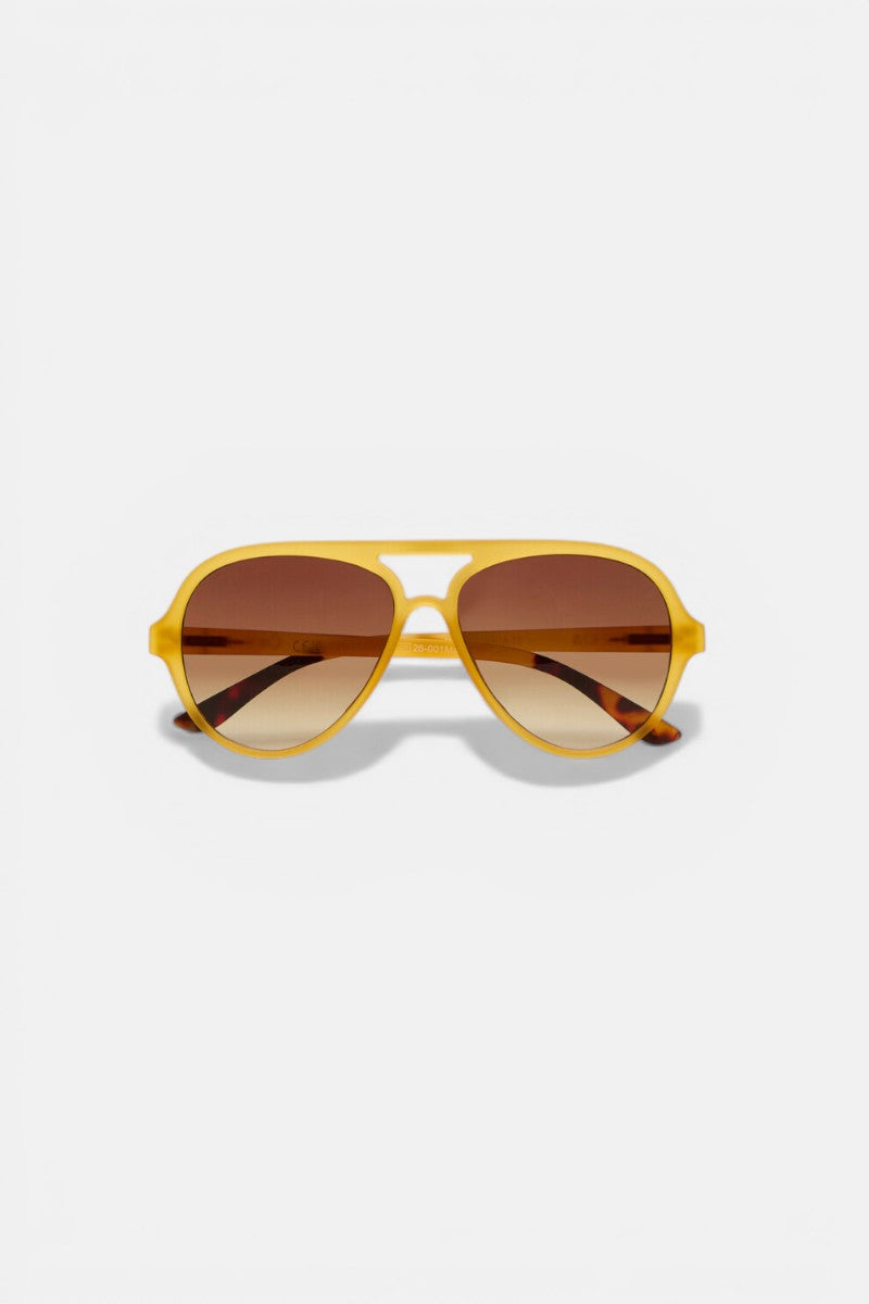 Okkia Yellow Aviator Sonnenbrille mit mattem Rahmen und braunen Verlaufsgläsern ist auf einem weißen Hintergrund zentriert. Diese Unisex-Sonnenbrille verfügt über UV 400 Schutz, mit einem Hauch von Orange an den Innenbügeln.