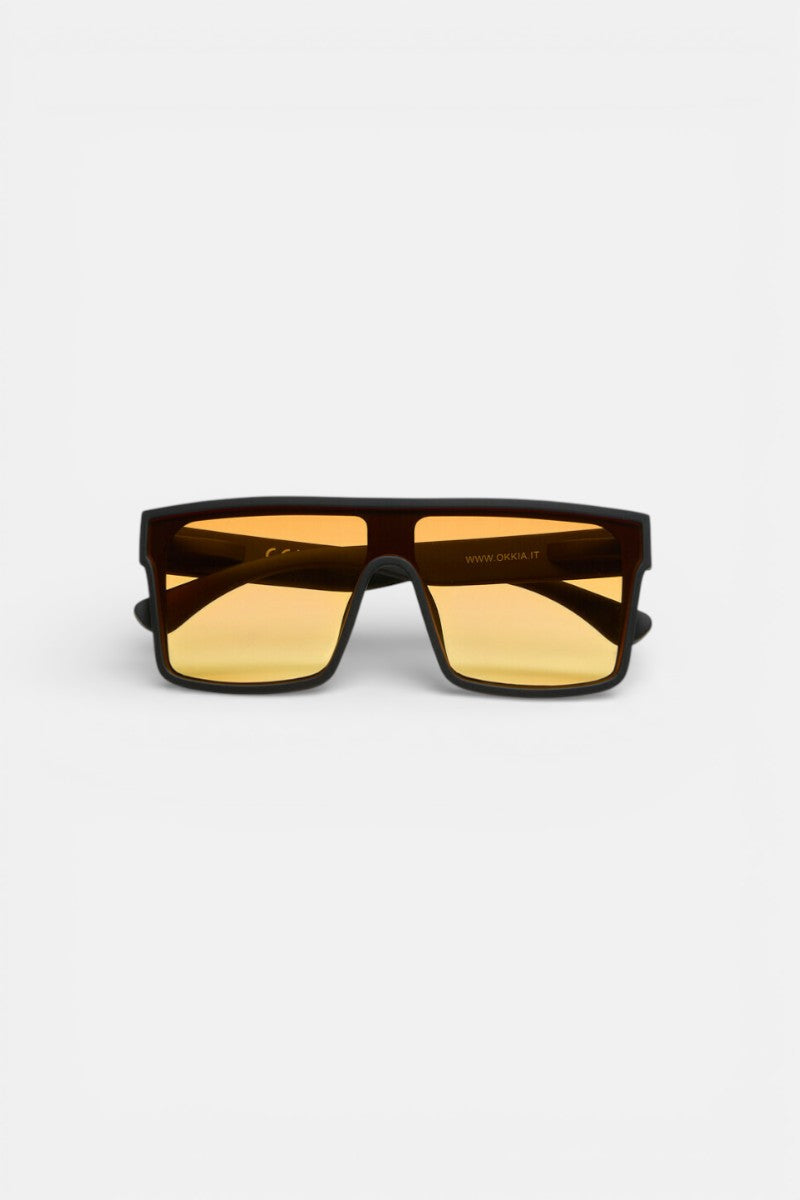 Ein Paar übergroße Okkia Sonnenbrille mit rechteckigem schwarzem Rahmen, großen flachen gelb-orangen Gläsern, kühnem modernen Design und UV 400-Schutz. Massive Bügel und ein gerader oberer Steg heben sich von einem schlichten weißen Hintergrund ab.