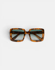 Eine quadratische Sonnenbrille mit einem breiten, braunen Schildpatt-Rahmen und dunklen, verlaufsgetönten Gläsern ist auf einem schlichten weißen Hintergrund zu sehen. Die Okkia CLUB Sonnenbrille besticht durch ein markantes, retro-inspiriertes Oversize-Design mit breiten Bügeln und polarisierten Gläsern, die sowohl Stil als auch optimalen Augenschutz bieten.