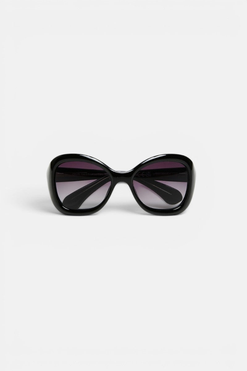 Eine schwarze, übergroße polarisierte Sonnenbrille von Okkia mit abgerundetem, eckigem Rahmen und dunklen Verlaufsgläsern wird vor einem schlichten weißen Hintergrund gezeigt, von vorne betrachtet, wobei die Bügel nach innen gebogen sind.