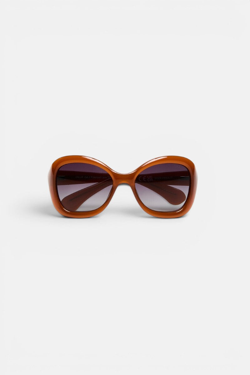 Breite, braune Okkia-Sonnenbrille mit quadratischem Rahmen und dunklen, leicht verlaufenden Gläsern. Die Okkia CLUB-Sonnenbrille ist zusammengeklappt vor einem schlichten weißen Hintergrund abgebildet, direkt von vorne betrachtet, um ihren dicken, glänzenden Rahmen und das retro-inspirierte Design hervorzuheben. Erleben Sie Stil und Komfort zugleich mit dieser polarisierten Sonnenbrille von Okkia, die für zeitlosen Charme geschaffen wurde.