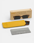 Eine schildpattfarbene polarisierte Sonnenbrille von Okkia, ein gelbes Okkia-Etui, ein graues Okkia-Putztuch und eine braune "polarisierte Mag Mask"-Magnetclip-Box sind ordentlich auf einem weißen Hintergrund angeordnet.