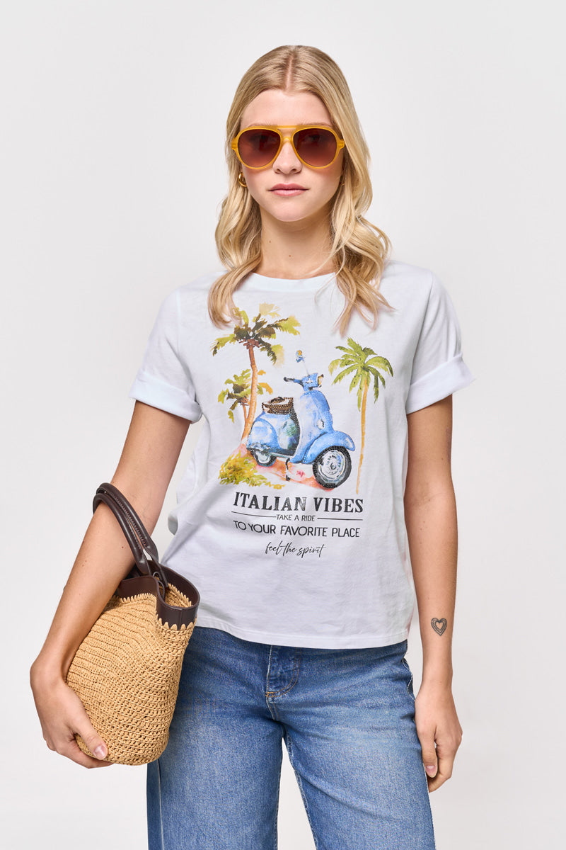 Eine Frau mit blondem Haar in lockeren Wellen, Sonnenbrille, Blue Jeans und einem Princess Goes Hollywood T-Shirt aus Baumwolle mit Vespa-Aufdruck und der Aufschrift "ITALIAN VIBES are one to your favorite place" trägt eine geflochtene Strohtasche vor einem schlichten Hintergrund.