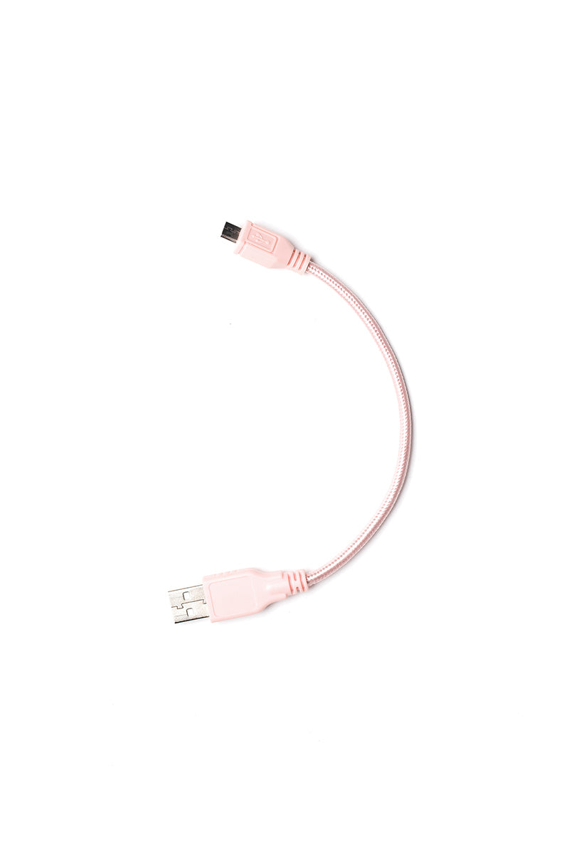 Ein kurzes, hellrosa Steamery-USB-Kabel mit einem USB-A-auf-Micro-USB-Stecker, leicht gebogen auf einem schlichten weißen Hintergrund - perfekt zum Laden Ihres Fusselrasierers oder ähnlicher Geräte.