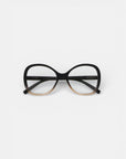 Eine Brille von Okkia mit großen, abgerundeten Rahmen im Schmetterlingsdesign, die von Schwarz zu Hellbraun übergehen, mit klaren Gläsern und einer Soft-Touch-Oberfläche. Die Brille ist auf einem schlichten weißen Hintergrund abgebildet.