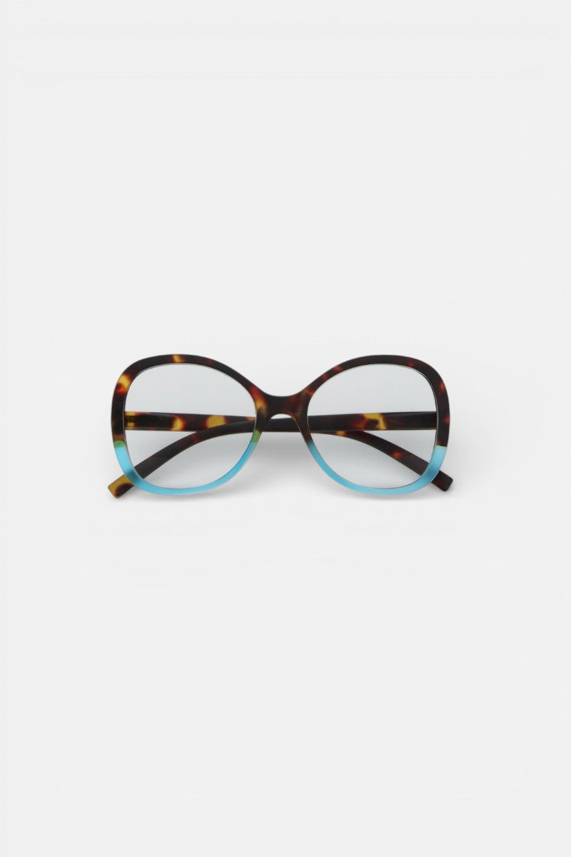 Die Okkia Lesebrille mit übergroßem, rundem Rahmen im Schmetterlingsstil hat eine obere Hälfte aus braunem Schildpatt und eine untere Hälfte in Hellblau. Vor einem schlichten weißen Hintergrund.