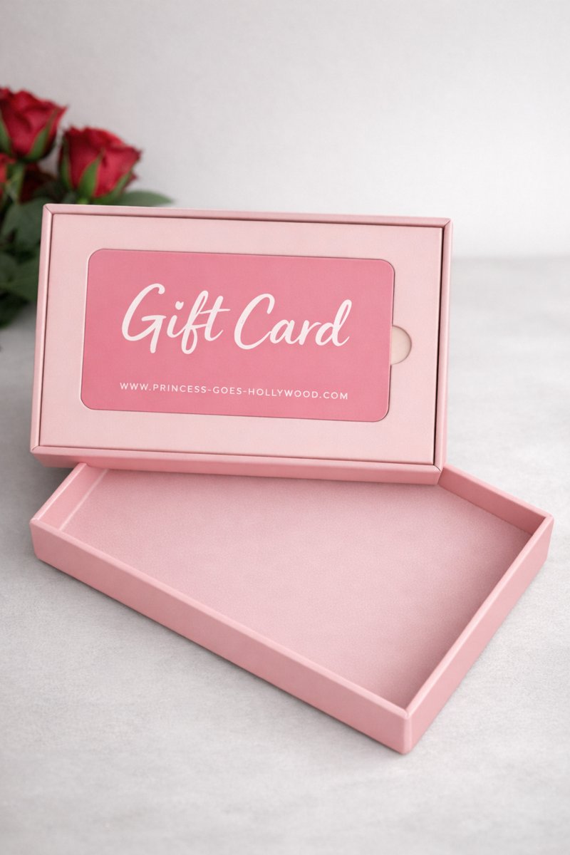Eine geöffnete rosafarbene Princess Goes Hollywood Geschenkkartenbox enthüllt eine passende Geschenkkarte im Inneren. Auf einer hellen Fläche mit roten Rosen im Hintergrund ist dieses elegante Display perfekt für jeden Mode-Liebhaber.
