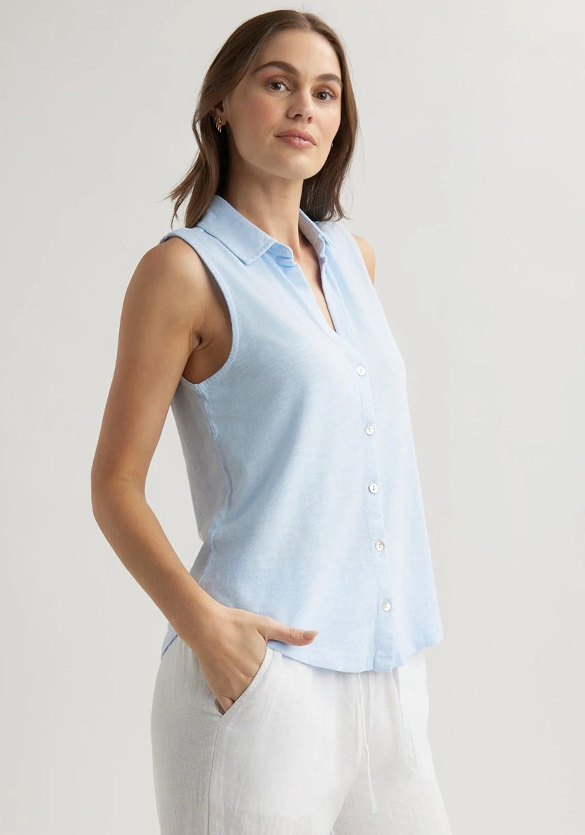A woman with light skin and brown hair wears a sleeveless Bella Dahl Baumwollmix Top with Hemdkragen in light blue and white pants, standing confidently with one hand in her pocket against a plain light background.
