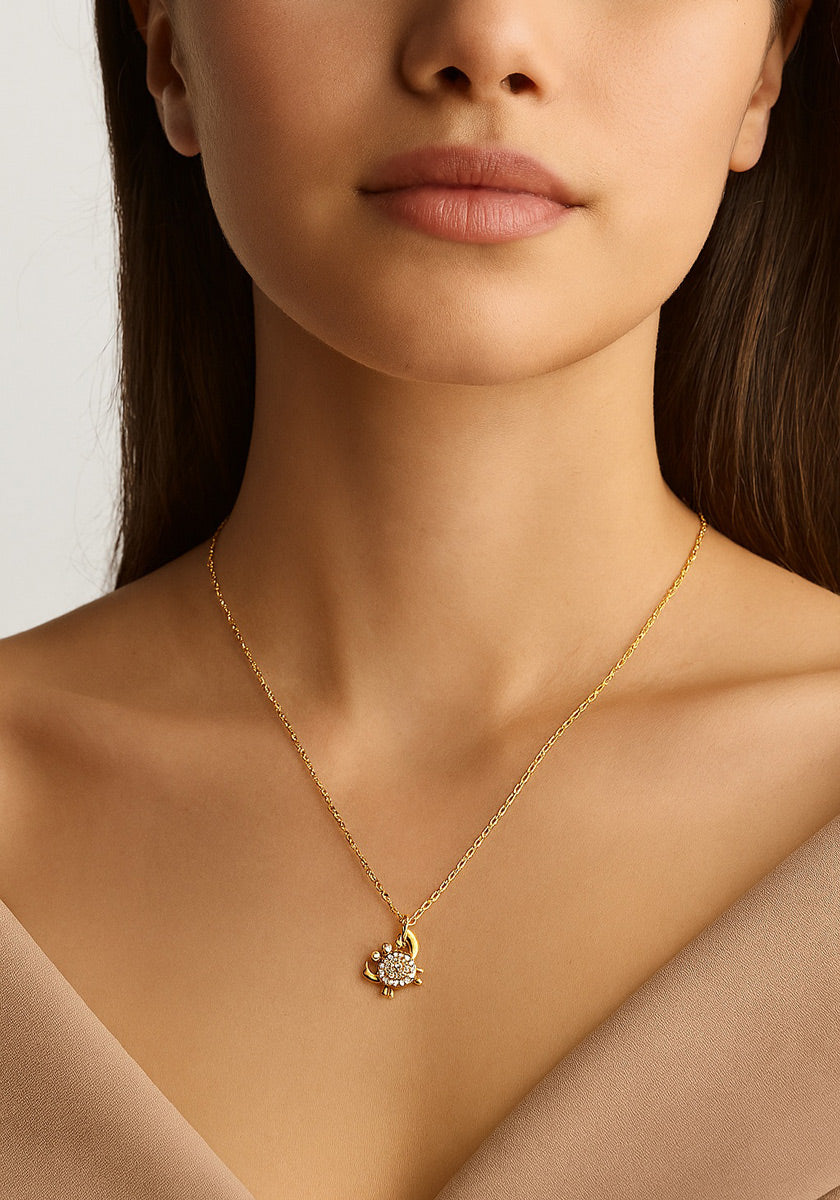 A woman in a V-neck beige top models the Princess Goes Hollywood filigrane Damenkette—a delicate gold chain necklace with a flower-shaped pendant and sparkling stones—shown cropped from shoulders up to highlight the jewelry.