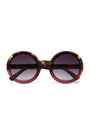 Okkia round sunglasses with oversized frames feature a tortoiseshell pattern on the top and outer edges, blending into translucent red at the bottom. The dark gradient lenses fade from black to light gray.